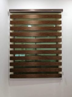 a window with wooden blinds hanging on the side of it in front of a white wall