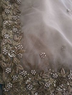 the back of a wedding dress with beading and flowers on it's side