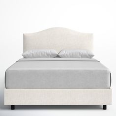 a white bed with two pillows on top of the headboard and foot board is shown