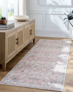 a pink rug on a wooden floor in front of a window with white walls and windowsill