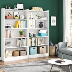 a living room with green walls and white bookcases filled with books on top of each shelf