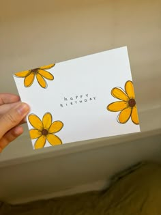 a person holding up a birthday card with yellow flowers on it and the words happy birthday