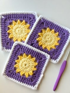 three crocheted squares with yellow and purple designs on them next to a knitting needle