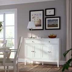 a dining room with white furniture and pictures on the wall