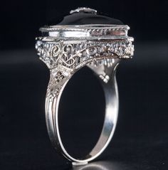 Vintage 1920's 14k White Gold Onyx Diamond Cocktail Style Ring .005ct 4.9gMetal Information: 14k White GoldTotal Weight: 4.9gBand Width: 1.8mmSize: 7.5Circa: 1920'sStone InformationMain StoneGem Type: OnyxShape: Marquise (18mm x 8mm)Color: BlackClarity/Quality: ANumber of Stones: 1Accent StonesGem Type: DiamondShape: Old Mine (1.0mm)Color: IClarity/Quality: SI1Carat Weight: .005ctNumber of Stones: 1Total estimated ctw (carat total weight): .005ctwEstimated Retail Price: $1875.00OUR PRICE: $1500.00SizingMany of our pieces can be re-sized at the buyers request. Please email us if you require our skilled professional services.46127 Antique Black Jewelry For Formal Occasions, Classic Black Filigree Ring For Formal Occasions, Black Filigree Ring With Intricate Design For Formal Occasions, Elegant Black Filigree Ring For Anniversary, Black Filigree Ring For Formal Occasions, Antique Black Jewelry With Polished Finish, Antique Black Wedding Jewelry, Antique Black Jewelry For Wedding, Formal Black Filigree Ring