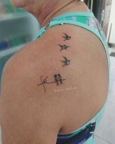 a woman's back shoulder with birds on it and the word love written in cursive writing