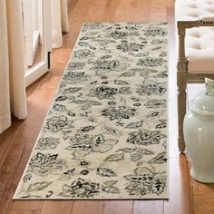 a white rug with black and blue designs on it in a living room next to a chair