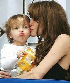 a woman kissing a baby while holding a bottle