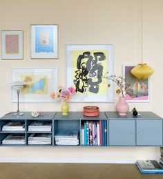 a shelf with books, vases and pictures on it