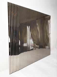 the reflection of two people in a mirror on a white surface with vertical slats