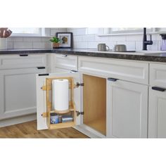 an open cabinet in a kitchen with white cabinets