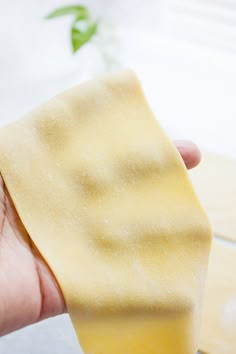 a hand holding a piece of food in it's left hand on top of a wooden table