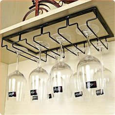 several wine glasses are hanging from a shelf