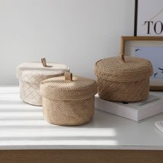 three woven baskets sitting on top of a table next to a phone and framed photograph