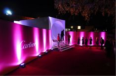 people are standing in front of a pink wall with the name cartier on it