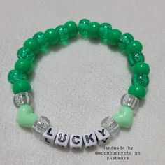 a green beaded bracelet with the word lucky written in white letters and beads on it