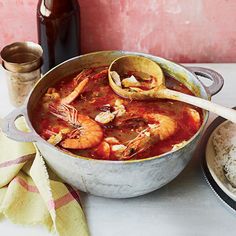 a large pot filled with food next to a wooden spoon and some rice on a table