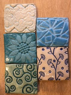 four different colored ceramic tiles sitting on top of a wooden table