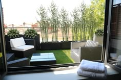 a balcony with grass, couches and potted plants