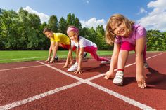 two children are on the starting line of a running track and one child is wearing pink