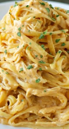 a white plate topped with pasta covered in sauce and garnished with parsley