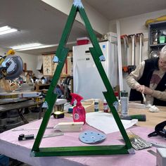 an older woman is making a christmas tree out of wood