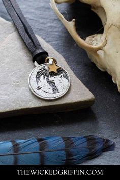 a necklace with an eagle on it sitting next to a bird's skull and feather