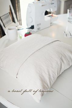 a white pillow sitting on top of a table next to a sewing machine