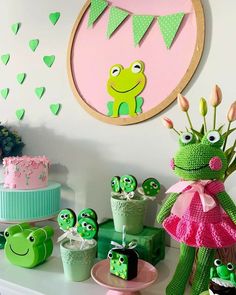 a table topped with cakes and cupcakes covered in green frosted icing