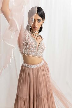 Editor's Note The embellished choli is paired with a tiered skirt featuring an embellished waistbelt. The outfit is completed with a net scalloped dupatta, creating an elegant and sophisticated look. Fabric: Choli: georgette, skirt: chiffon, dupatta: net, satin lining Color: Dusty pink Components: Lehenga, blouse and dupatta Occasion: Engagement, festive and wedding guest Disclaimer: Product color may slightly vary due to photographic lighting sources or your monitor setting. Care: Dry clean onl Designer Party Wear Skirt Set With Dupatta, Elegant Festive Skirt Set With Resham Embroidery, Elegant Designer Zari Work Skirt Set, Elegant Georgette Skirt Set For Reception, Elegant Designer Skirt Set With Zari Work, Anarkali Skirt Set With Sheer Dupatta, Elegant Festive Saree Skirt Set, Festive Georgette Skirt Set For Reception, Elegant Floor-length Designer Skirt Set