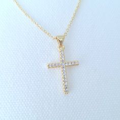 This small 14K gold filled, cubic zirconia necklace is filled with radiant, CZ pave stones. It is the perfect gift for Easter, First Communion or any religious occasion. It looks beautiful alone or layered with other necklaces to complete a minimalist look.  * 2.5cm x 1.3cm Gold Filled Cross With Cubic Zirconia Stones * Custom Length 14K Gold Filled Chain * 2" Extender Can Be Added * Hypoallergenic, Lead & Nickel Free * Tarnish Free * Stamped With 14K/20 On Clasp For Authenticity * Comes In An O Gold Necklaces With Cubic Zirconia Sparkling Stones, Gold Necklace With Cubic Zirconia Sparkling Stones, Gold Diamond Rhinestone Necklace As Gift, Gift Cross Necklace With Diamond Accents In Cubic Zirconia, Gold Rhinestone Necklace With Diamond Accents As Gift, Gold Diamond Necklace With Sparkling Stones As Gift, Gold Crystal Rhinestone Cross Pendant Necklace, Gold Dainty Crystal Necklace With Cubic Zirconia, Gold Dainty Cubic Zirconia Crystal Necklace