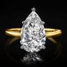 a pear shaped diamond ring on a black background