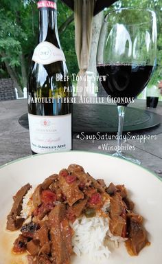 a white plate topped with rice and meat next to a bottle of wine