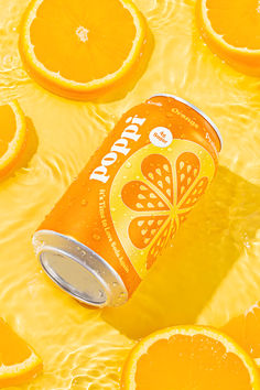 a can of orange soda surrounded by sliced oranges