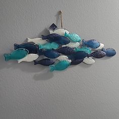 a group of blue and white fish hanging on a wall next to a gray wall