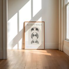 a framed poster on the wall in an empty room with sunlight coming through the windows