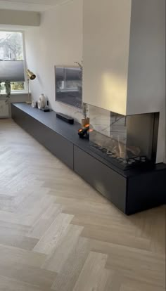 a living room with white walls and wood flooring on the side, along with a fireplace