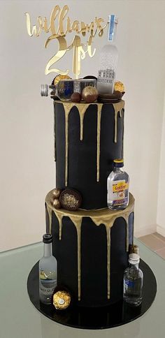 a black and gold birthday cake with chocolate drizzles on the top tier