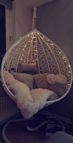 a white hanging chair with pillows and lights