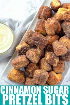 cinnamon sugar pretzel bites on a white plate next to a bowl of cream