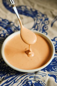 a spoon full of caramel sauce on top of a blue and white table cloth