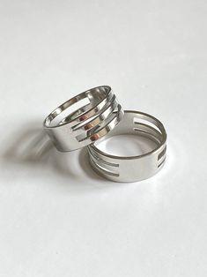 two silver rings sitting next to each other on a white surface with one ring in the middle