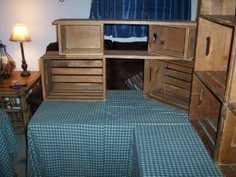 a bed room with a neatly made bed and wooden cabinets on the wall next to it