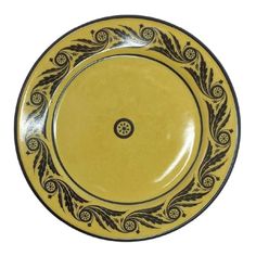 a yellow and black plate with an ornate design on the rim, set against a white background