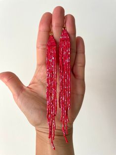 a hand holding two red beaded tassels