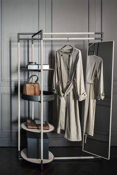 a coat rack with two coats hanging on it's sides and a purse next to it