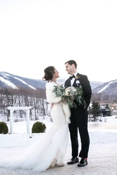 a bride and groom standing in the snow