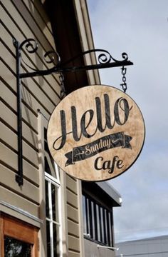 a sign hanging from the side of a building that says hello sunday cafe on it