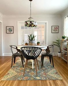 a dining room table with four chairs and a potted plant on top of it