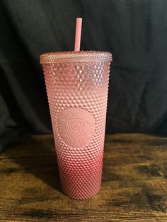 a pink starbucks cup sitting on top of a wooden table